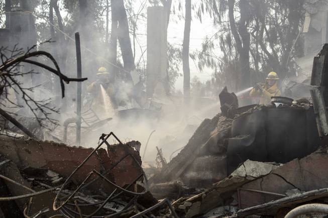 Firefighters put out hot spots at the Singer Mansion after it burned down during a wildfire burns just north of the San Gabriel Valley community of Glendora, Calif., on Thursday, Jan 16, 2014. 