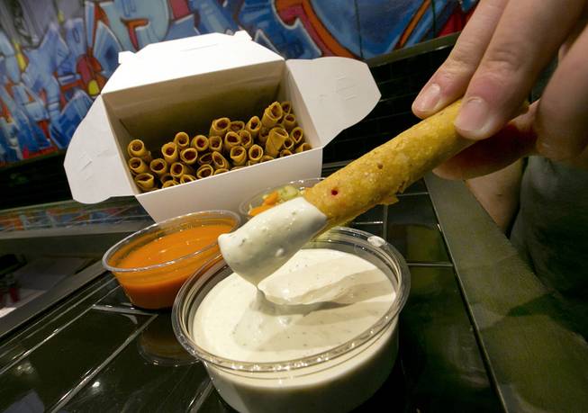 A buffalo chicken taquito is dipped in blue cheese dressing at Taquitoria, on New York's Lower East Side, on Tuesday, Jan. 14, 2014. 