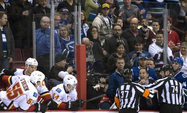Referees get in the way of Vancouver Canucks head coach John Tortorella as he screams at the Calgary Flames bench during first period NHL hockey action at Rogers Arena in Vancouver, British Columbia Saturday Jan. 18, 2014.