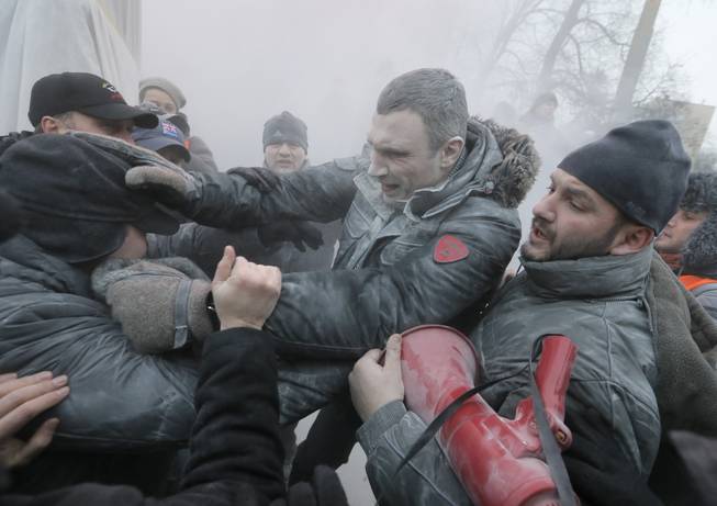 Opposition leader and former WBC heavyweight boxing champion Vitali Klitschko, center, is attacked and sprayed with a fire extinguisher as he tries to stop the clashes between police and protesters  in central Kiev, Ukraine, Sunday, Jan. 19, 2014. Hundreds of protesters on Sunday clashed with riot police in the center of the Ukrainian capital, after the passage of harsh anti-protest legislation last week seen as part of attempts to quash anti-government demonstrations. A group of radical activists began attacking riot police with sticks, trying to push their way toward the Ukrainian parliament building, which has been cordoned off by rows of police and buses. 