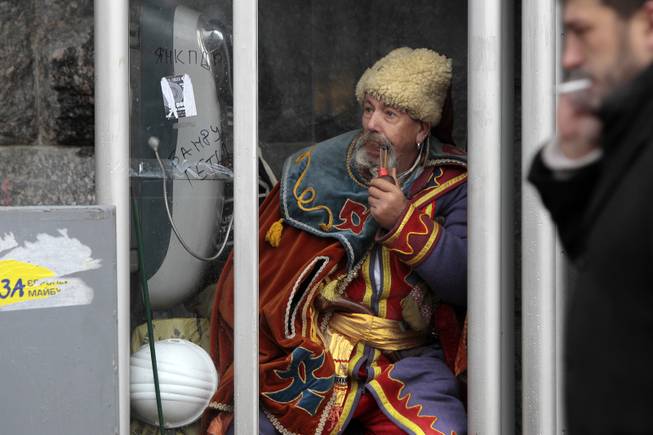 An anti-government protester sits in a telephone booth in Kiev, Ukraine, Friday, Dec. 6, 2013. A leader of the protests gripping Ukraines capital to try to force the governments resignation says the opposition is willing to talk with officials to find a way out of the crisis, but only if the police who violently dispersed demonstrators are punished. 