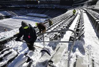 Workers shovel snow off the seating area at MetLife Stadium as crews removed snow ahead of Super Bowl XLVIII following a snow storm, Wednesday, Jan. 22, 2014, in East Rutherford, N.J. Super Bowl XLVIII, which will be played between the Denver Broncos and the Seattle Seahawks on Feb. 2, will be the first NFL title game held outdoors in a city where it snows.