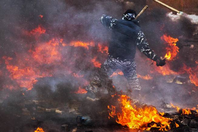 A protester prepares to throw a Molotov cocktail during clashes with police in central Kiev, Ukraine, Wednesday, Jan. 22, 2014. Two people whose dead bodies were found Wednesday near the site of clashes with police have been shot with live ammunition, prosecutors said Wednesday, an announcement that could further fuel violence that spilled on the streets of the Ukrainian capital after two months of largely peaceful protests.