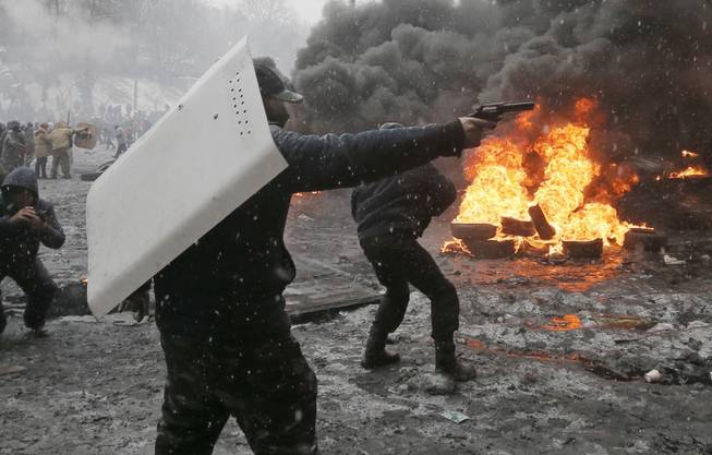 A protester points a handgun during a clash with police in central Kiev, Ukraine, Wednesday, Jan. 22, 2014. Three people have died in clashes between protesters and police in the Ukrainian capital Wednesday, according to medics on the site, in a development that will likely escalate Ukraine's two month-long political crisis. 