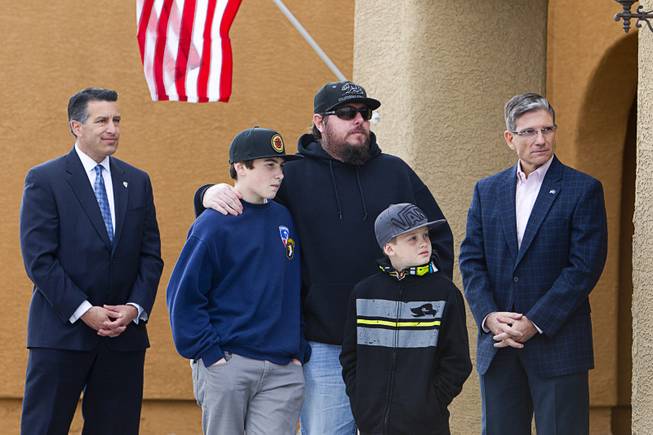 Army Sgt. Christopher Bales, center, and his sons Keenan, 14, and Aiden, 8, listen to speakers during a new home dedication at the Coldwater Crossing subdivision in the Mountain's Edge master planned community Thursday Jan. 23, 2014. Flanking the family are Nevada Governor Brian Sandoval, left, and Congressman Joe Heck (R-NV). Pulte Homes, along with other companies, presented the home to Bales as part of Operation Finally Home," an organization which provides homes to veterans and the families of fallen servicemen.