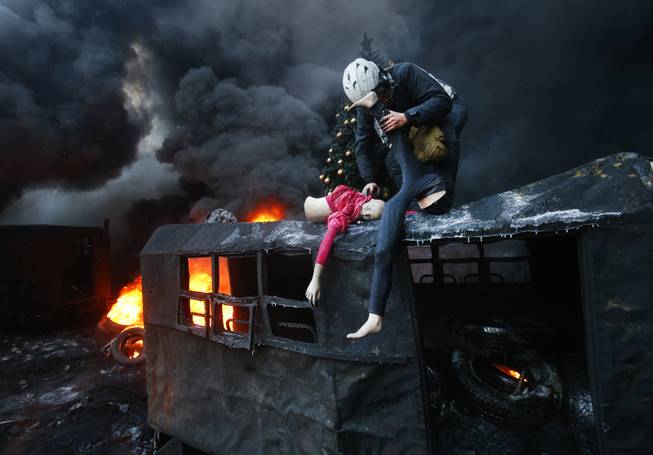 A protester breaks up a mannequin on the roof of the burned truck during clashes with police in central Kiev, Ukraine, Thursday Jan. 23, 2014. 