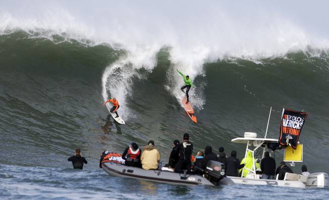 Shane Dorian, left, and Ben Wilkinson, right, catch a wave during the third heat of the first round of the Mavericks Invitational big wave surf contest Friday, Jan. 24, 2014, in Half Moon Bay, Calif.