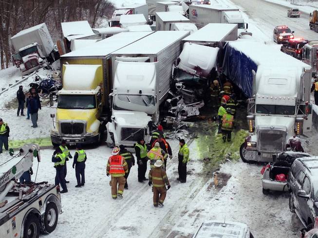 In this photo provided by the Indiana State Police, emergency crews work at the scene of a massive pileup involving more than 40 vehicles, many of them semitrailers, along Interstate 94, Thursday afternoon, Jan. 23, 2014, near Michigan City, Ind. At least three were killed and more than 20 people were injured.
