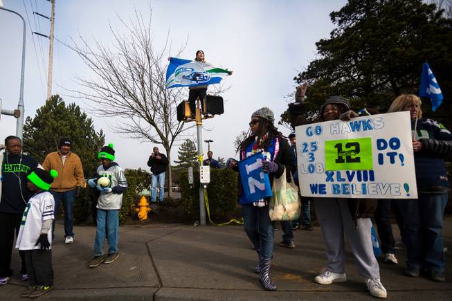 High above the crowd and perched on a crosswalk sign, Kristian Martinez, 22, rallied with thousands of diehard 12thMan fans on South 188th Street to see off the Seahawks team buses on their way to the airport en route to New York for Super Bowl XLVIII, Sunday, Jan. 26, 2014, in SeaTac, Wash.