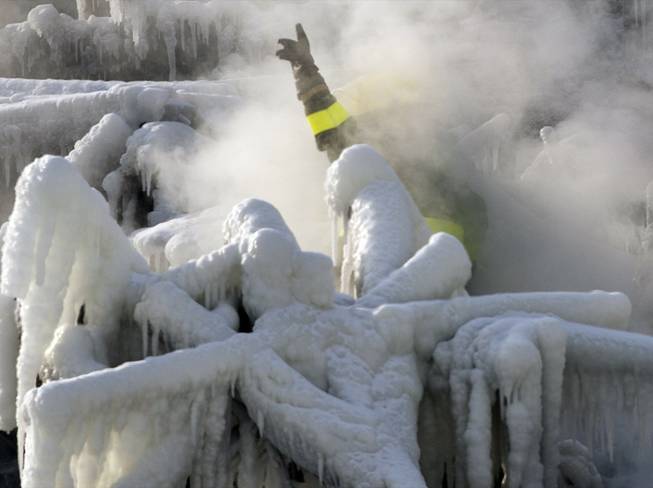 A police investigator, enveloped in steam, signals to colleagues as they search through the icy rubble of a fire that destroyed a seniors' residence Friday, Jan. 24, 2014, in L'Isle-Verte, Quebec. 