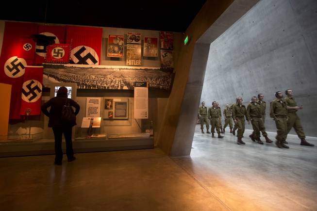 A visitor looks at an exhibit as Israeli soldiers walk at the Yad Vashem Holocaust memorial in Jerusalem, ahead of the International Holocaust Remembrance Day, Sunday, Jan. 26, 2014.  