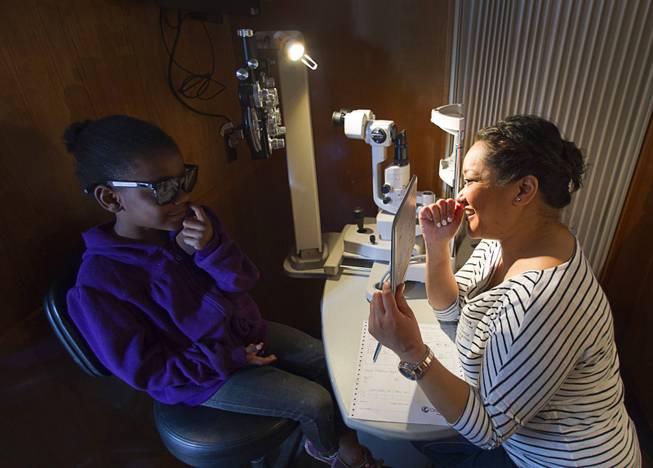 Kindergarden student Tashiani Sewell, 6, looks at a 3D image held by optometrist Erin Frillarte in the OneSight mobile vision center at the Andre Agassi College Preparatory Academy Tuesday, Jan. 27, 2014. Over 100 Clark County School District students received free eye exams and new glasses. OneSight is an organization providing access to eye care and eyewear to underserved communities.