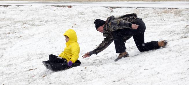 A parent gives his child a push down the hills that surround the soccer fields at Belhaven University in Jackson, Miss., Tuesday, Jan. 28, 2014. An arctic blast spread across Mississippi with below freezing temperatures and treacherous driving conditions. 
