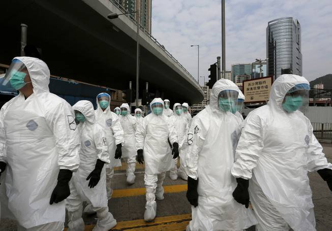 Health workers in full protective gear walk at a wholesale poultry market before culling the poultry in Hong Kong, Tuesday, Jan. 28, 2014.