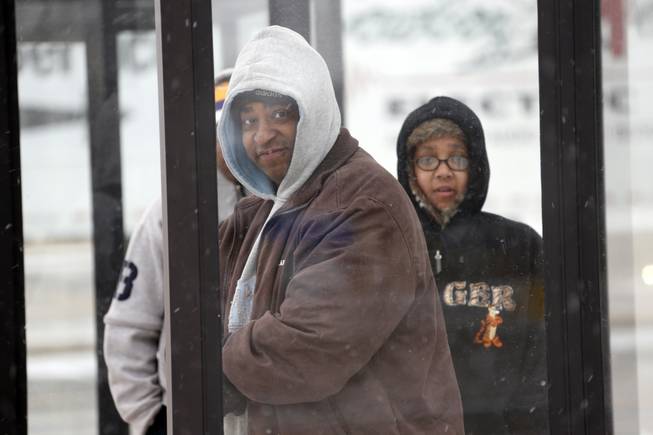 Richard Robinson of Jackson and others wait under a shelter for their morning bus ride into downtown Jackson, Miss., Tuesday, Jan. 28, 2014, as ice and snow flurries have brought on difficult driving conditions. A severe winter storm is expected to hit the state bringing ice and snow to the Gulf Coast. Snow is expected to get heavier though mid-morning before temperatures rise by early afternoon. 