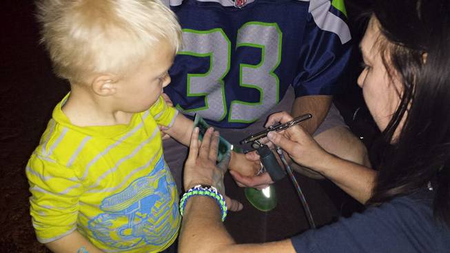 A little boy has the Seahawks logo airbrushed on his arm during a Seahawks vs. Vikings Charity event at Scooter's Pub.