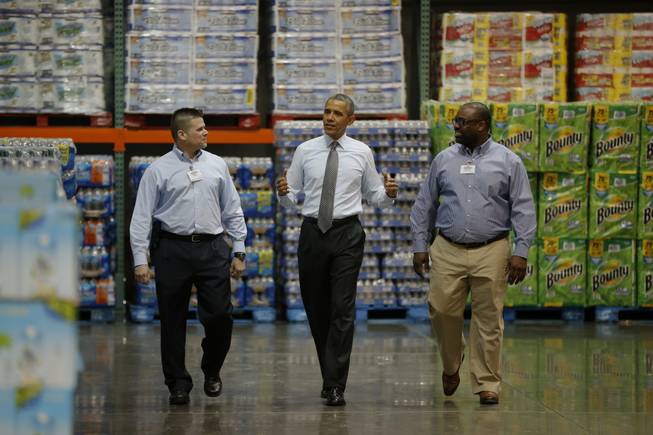 President Barack Obama walks with Ricky Banner, assistant general manager, right, and Emile (Ray) Quevedo, floor employee, at a Costco store in Lanham, Md., Wednesday, Jan. 29, 2014, before he spoke about raising the minimum wage.