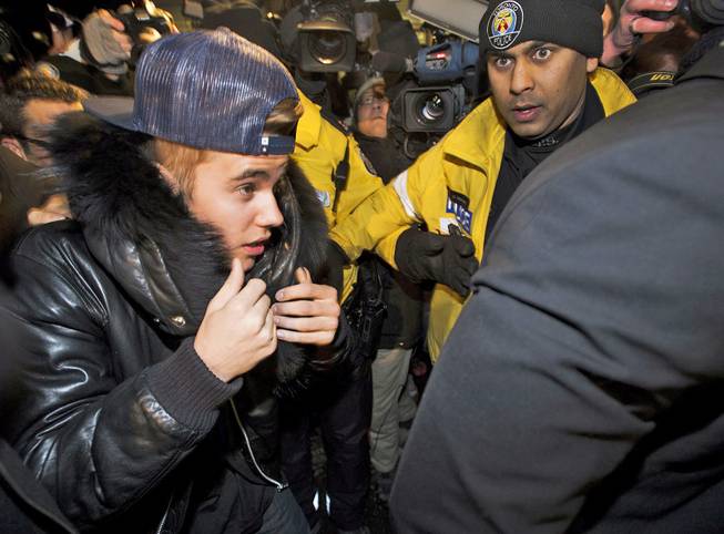 Singer Justin Bieber is swarmed by media and police officers as he turns himself in to city police for an expected assault charge in Toronto on Wednesday, Jan. 29, 2014. 