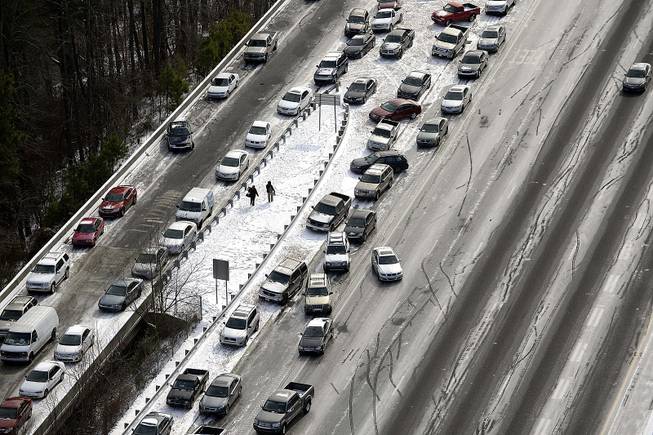 In this aerial view looking at I-75 north at Mt. Paran Road, abandoned cars are piled up on the median of the ice-covered interstate after a winter snow storm Wednesday, Jan. 29, 2014, in Atlanta. 