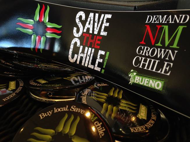 In this July 31, 2013, image, a collection of bumper stickers and buttons promoting New Mexico-grown chile sits on the order counter at Hello Deli restaurant in Albuquerque.