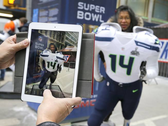 Tess DiMalanta, from the Philippines, poses for a photo in a Seattle Seahawks cut out along Super Bowl Boulevard Friday, Jan. 31, 2014, in New York. The Denver Broncos and Seahawks will face off Sunday in Super Bowl XLVIII in East Rutherford, NJ. 