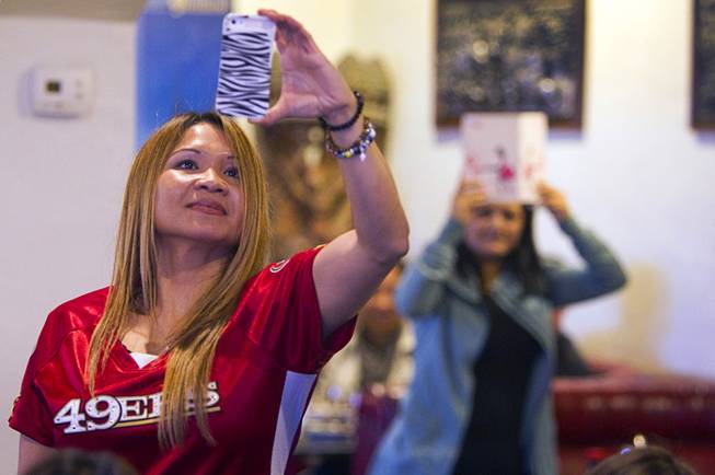 Phalenny Boswell takes a video with her phone during a lion dance at the Kung Fu Thai & Chinese Restaurant, 3505 S. Valley View Blvd. Sunday, Feb. 2, 2014. The traditional ceremony, performed by the Lohan School of Shaolin, was staged to drive out any evil spirits from the business.