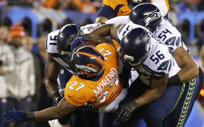 Denver Broncos' Knowshon Moreno (27) is tackled by Seattle Seahawks' Chris Clemons (91), Bobby Wagner and Cliff Avril (56) during the first half of the NFL Super Bowl XLVIII football game Sunday, Feb. 2, 2014, in East Rutherford, N.J. (AP Photo/Ted S. Warren)