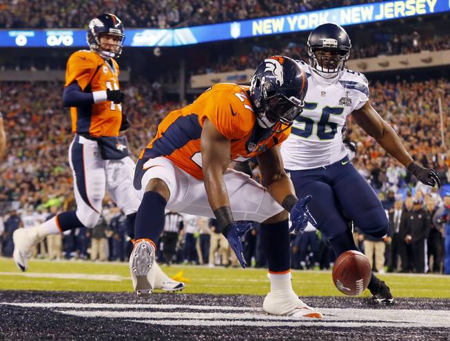 Denver Broncos' Knowshon Moreno reaches for a loose ball after the snap passed teammate Peyton Manning, left, during the first half of the NFL Super Bowl XLVIII football game Sunday, Feb. 2, 2014, in East Rutherford, N.J. Seattle Seahawks' Cliff Avril approached at right.