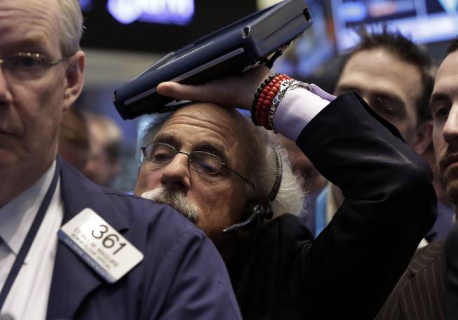 Trader Peter Tuchman rests his handheld device on his head as he works on the floor of the New York Stock Exchange Friday, Jan. 31, 2014.
