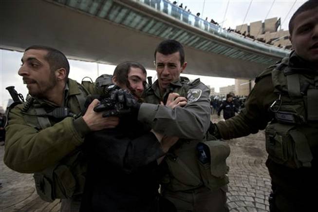 Israeli border police officers detain an ultra-Orthodox Jewish man during a demonstration in Jerusalem, Thursday, Feb. 6, 2014. Israeli police said thousands of ultra-Orthodox Jews are blocking highways across the country to protest plans to enlist them into the military.