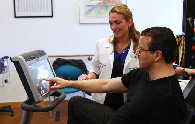 Physical therapist Jen Nash and Kerry Simon play mahjong while Simon rides an exercise bike during a therapy session at the Cleveland Clinic Lou Ruvo Center for Brain Health on Feb. 7, 2014.