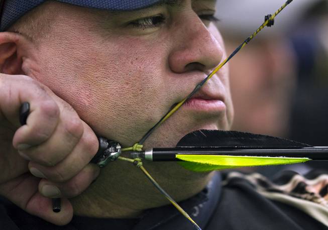 Archer Bernard Ortiz of Riverside, Calif., prepares to release another arrow snugged up to his face on Friday, Feb. 7, 2014. He shot one of the top scores during the Adult Freestyle Championship in the South Point Arena in the Vegas Round of the 2014 NFAA World Archery Festival.