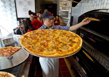 Chef Jorge Torres pulls another freshly baked pie from the oven at Pin-Up Pizza.