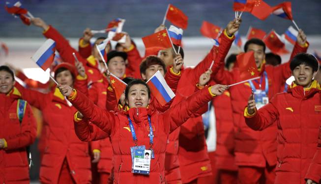 Members of the Chinese team wave Russian and Chinese flags as they arrive during the opening ceremony of the 2014 Winter Olympics in Sochi, Russia, Friday, Feb. 7, 2014.
