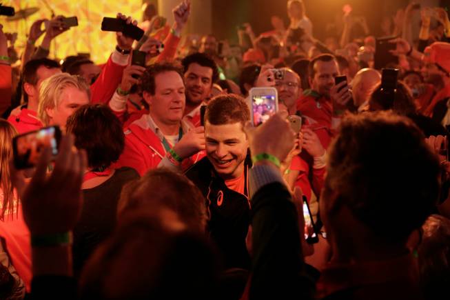 Under orange lighting, gold medallist Sven Kramer of the Netherlands walks through a crowd of cheering fans after winning the gold in the men's 5,000-meter speedskating race at the 2014 Winter Olympics in Sochi, Russia, on Saturday, Feb. 8, 2014. Kramer set a new Olympic record in the race.