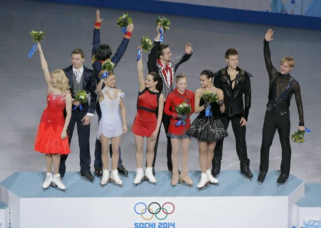 The Russian team waves to spectators from the podium during the flower ceremony after placing first in the team figure skating competition at the Iceberg Skating Palace during the 2014 Winter Olympics, Sunday, Feb. 9, 2014, in Sochi, Russia.