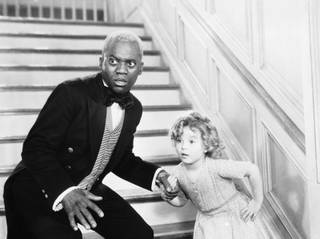 Bill Robinson as the butler is caught in the act of teaching Shirley Temple his world famous stair dance in a scene from 