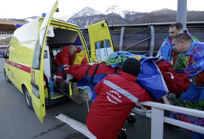 A track worker is loaded into an ambulance after he was injured when a forerunner bobsled hit him just before the start of the men's two-man bobsled training at the 2014 Winter Olympics, Thursday, Feb. 13, 2014, in Krasnaya Polyana, Russia.