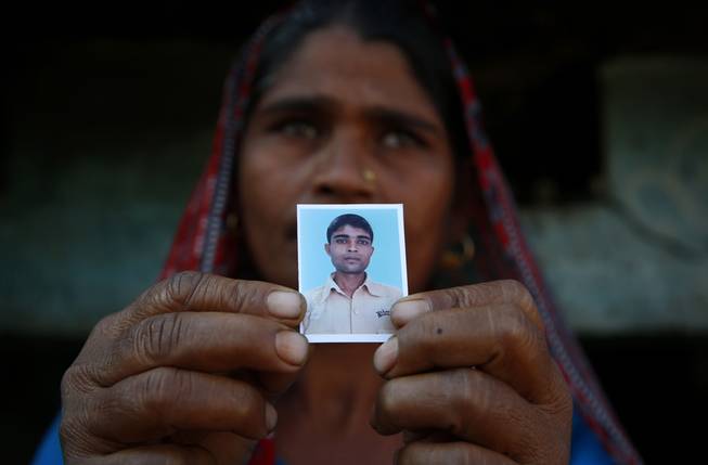 In this Wednesday, Feb. 12, 2014, photo, Taravati, who uses only one name, shows a photograph of her son Shiv Kumar Singh, a daily wage laborer, who was killed by a tiger at Maniawala, in northern India. The tiger that killed Singh on Jan. 10 has killed at least nine people so far traveling over 120 miles of villages, small towns and even a highway, spreading fear amongst the villagers many of whom are either farmers or laborers working the the large swathes of sugarcane fields which need harvesting now.