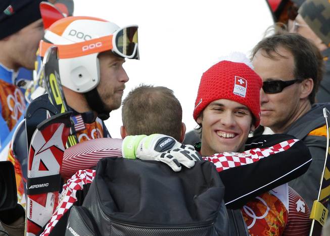 Men's supercombined gold medalist, Switzerland's Sandro Viletta, right, embraces another athlete as United States' Bode Miller, left, stands nearby in the finish area of the Alpine ski venue at the Sochi 2014 Winter Olympics, Friday, Feb. 14, 2014, in Krasnaya Polyana, Russia.