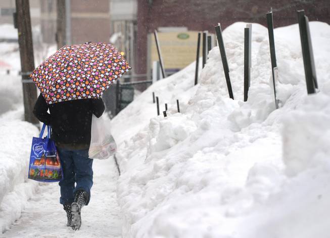 Pam Yeaple walks home after grocery shopping in York, Pa., on Saturday, Feb. 15, 2014. An inch of new snow had fallen by midday in much of eastern Pennsylvania on Saturday. Forecasters predicted 2 to 5 inches before evening.