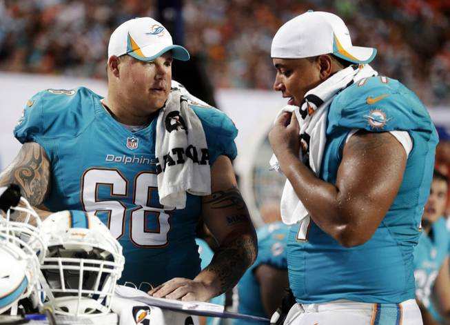 In this Aug. 24, 2013, file photo, Miami Dolphins guard Richie Incognito (68) and tackle Jonathan Martin (71) look over plays during an NFL preseason football game against the Tampa Bay Buccaneers in Miami Gardens, Fla. Martin was subjected to "a pattern of harassment" that included racist slurs and vicious sexual taunts about his mother and sister by three teammates, according to a report ordered by the NFL. The report said Incognito, who was suspended by the Dolphins in November, and fellow offensive linemen John Jerry and Mike Pouncey harassed Martin.