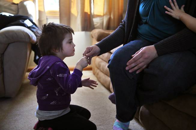 In this Feb. 7, 2014 photo, Elizabeth Burger, 4, holds her mother's hand at home in Colorado Springs, Colo. Elizabeth suffers from severe epilepsy and is receiving experimental treatment with a special strain of medical marijuana, which she takes orally as drops of oil.