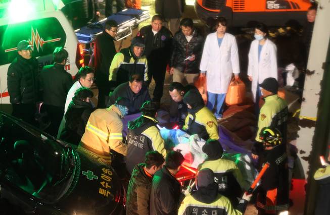 Rescue workers carry a victim, medical condition unknown, from a collapsed resort building in Gyeongju, South Korea, Monday, Feb. 17, 2014.  South Korean police and news reports say that dozens of university students are feared trapped after a buildingis roof collapsed because of recent heavy snowfall.