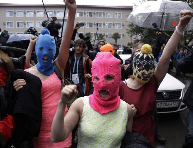 Russian punk group Pussy Riot members Nadezhda Tolokonnikova, in the blue balaclava, and Maria Alekhina, in the pink balaclava, make their way through a crowd after they were released from a police station, Tuesday, Feb. 18, 2014, in Adler, Russia. 