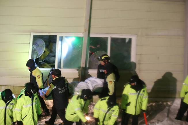 Rescue workers carry a body from a collapsed building in Gyeongju, South Korea, Monday, Feb. 17, 2014. South Korean police and news reports say that dozens of university students are feared trapped after a buildingis roof collapsed because of recent heavy snowfall.