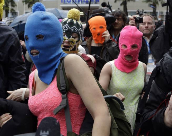 Russian punk group Pussy Riot members Nadezhda Tolokonnikova, in the blue balaclava, and Maria Alekhina, in the pink balaclava, make their way through a crowd after they were released from a police station, Tuesday, Feb. 18, 2014, in Adler, Russia. No charges were filed against Tolokonnikova and Alekhina along with the three others who were detained.