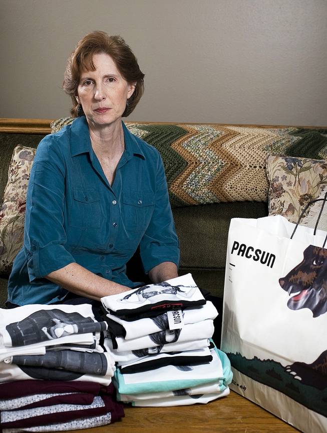 Judy Cox sits for a portrait next to a stack of T-shirts with what she believes are pornographic designs Monday, Feb. 17, 2014, in Orem, Utah. 