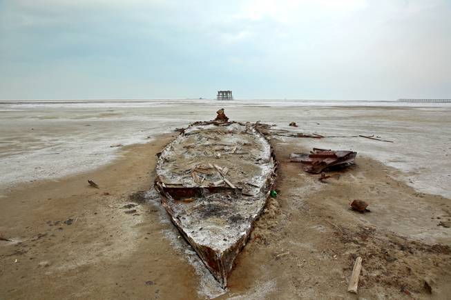 In this Sunday, Feb. 16, 2014 photo, the wreckage of a boat is stuck in the solidified salts and sands at Lake Oroumieh, northwestern Iran.