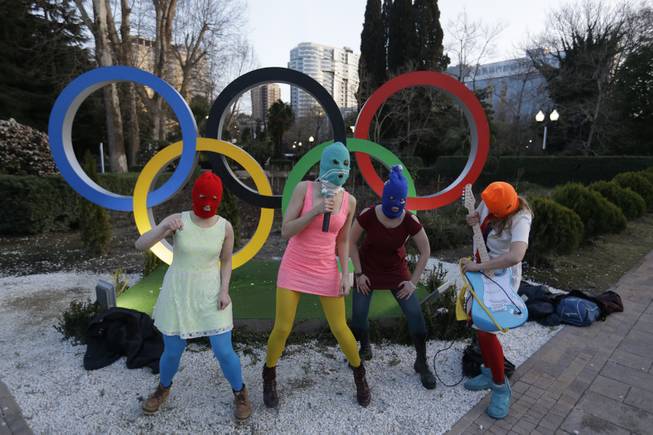 Members of the punk group Pussy Riot, including Nadezhda Tolokonnikova in the aqua balaclava, center, and Maria Alekhina in the red balaclava, left, perform next to the Olympic rings in Sochi, Russia, on Wednesday, Feb. 19, 2014. 